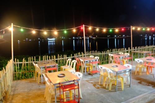 a group of tables and chairs with lights on a fence at Wan Resort Rayong in Ban Laem Makham