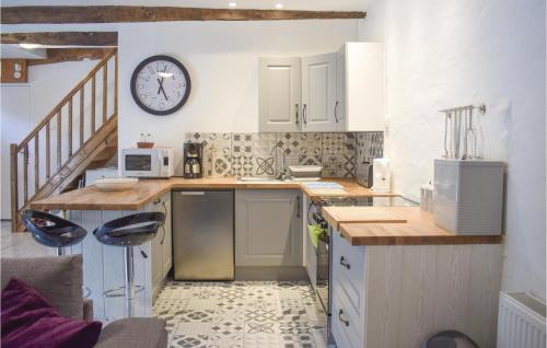 une cuisine avec un comptoir et une horloge au mur dans l'établissement Cozy Home In Callac De Bretagne, à Callac