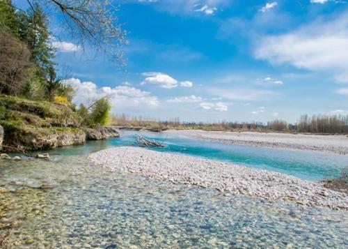 a river with blue water and rocks on the shore at Casa Nostra in Selva del Montello