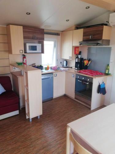 - une petite cuisine avec des armoires blanches et des appareils bleus dans l'établissement Bungalow confortable à Vias avec piscine partagée, à Vias