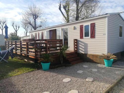 ein weißes winziges Haus mit einem Holzzaun in der Unterkunft Bungalow confortable à Vias avec piscine partagée in Vias