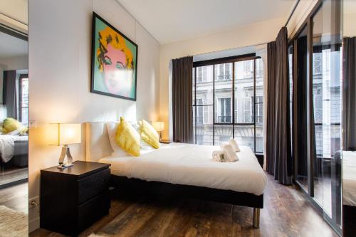 une chambre avec un lit et une grande fenêtre dans l'établissement MBM - Paradis, à Paris