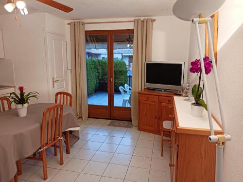 uma sala de estar com uma mesa e uma televisão em Maison de 2 chambres avec piscine partagee terrasse amenagee et wifi a Vias em Vias