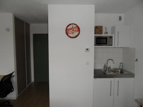 una cocina con fregadero y un reloj en la pared en # STUDIO BON EMPLACEMENT AVEC PARKING #, en Illzach