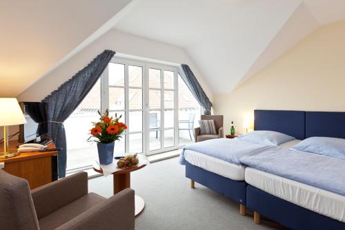um quarto com uma cama azul e uma grande janela em Hotel Ingeborg em Waren