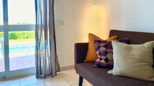 a couch with pillows in a living room with a window at Casa de Campo LAGOA DOS SALGADOS in Pêra