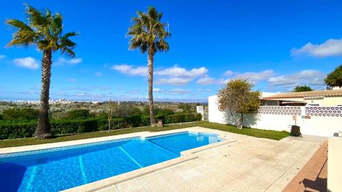 a swimming pool in front of a house with palm trees at Casa de Campo LAGOA DOS SALGADOS in Pêra