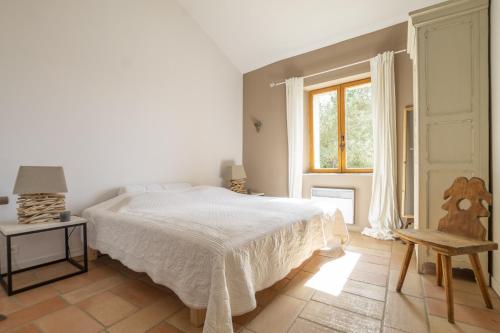 a white bedroom with a bed and a window at La Douce France in Les Taillades