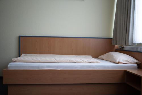 a bed with a wooden headboard and white sheets at RadlStadl - Brauhaus und Hotel in Kaarst