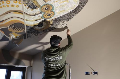 a man painting a mural on a ceiling at Muraless Art Hotel - WorldHotels Crafted in Castel d'Azzano