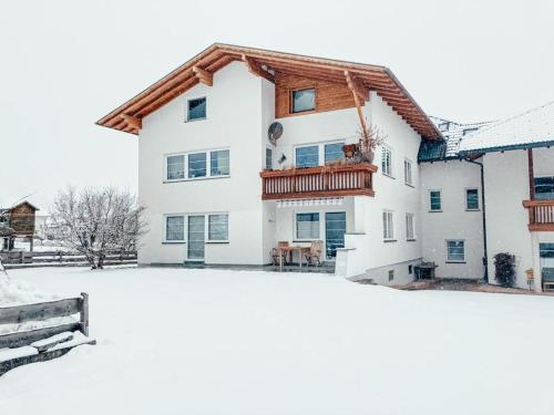 a white house with a wooden roof in the snow at Ferienwohnung Olympia Axams in Innsbruck