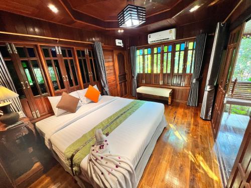 a bedroom with a large bed in a room with windows at บ้านสวนในฝัน-ตลาดน้ำท่าคา in Samut Songkhram