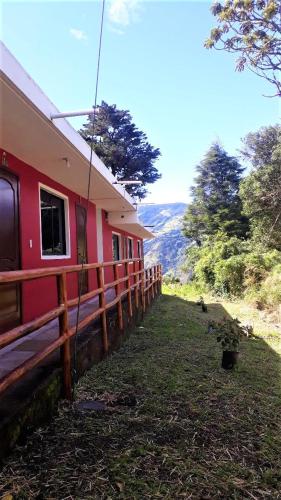a red house with a fence next to a field at La Estancia de Runtún Km 7 in Baños