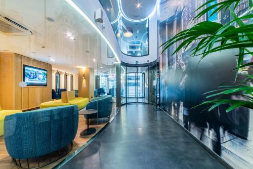 a lobby with blue chairs and plants in a building at Hotel Indigo Madrid - Gran Vía by IHG in Madrid