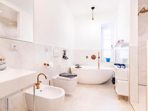 een witte badkamer met een bad, een toilet en een wastafel bij Ostseeresidenz Lidia mit Terrasse und Meerblick in Sassnitz