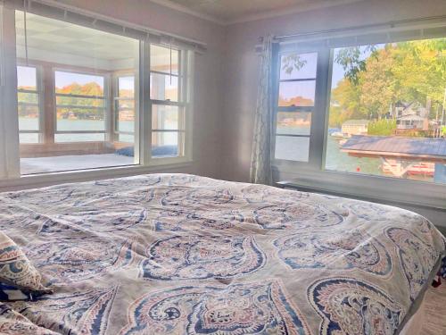 a bedroom with a large bed with two windows at Lake Front Home Near Peek'n Peak in Findley Lake