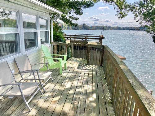 a deck with two chairs and a bench on the water at Lake Front Home Near Peek'n Peak in Findley Lake