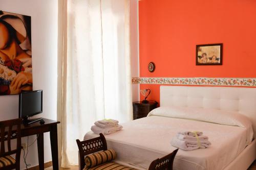 パオラにあるVilla Catalanoのオレンジ色の壁のベッドルーム1室、ベッド1台(椅子2脚付)