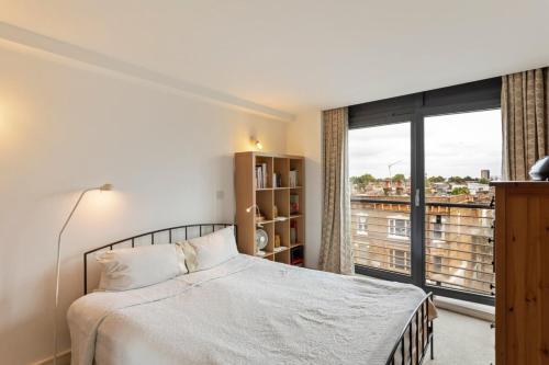 a bedroom with a bed and a large window at Breathtaking 2 Bedroom Apartment with Balcony near Stoke Newington in London