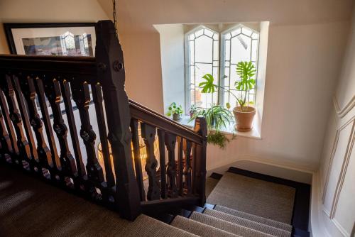 a stairwell with a wooden staircase with a window and plants at Halford House - Adults Only in Bourton on the Water