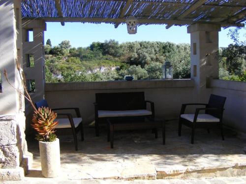 um pátio com cadeiras, uma mesa e uma janela em Masseria Pelosella B&B em Fasano