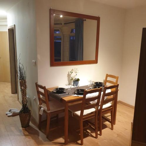 a dining room table with chairs and a mirror at Magyartenger Apartman Balatonlelle in Balatonlelle