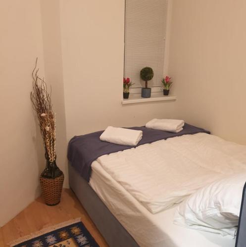a bedroom with a bed and a window with plants at Magyartenger Apartman Balatonlelle in Balatonlelle