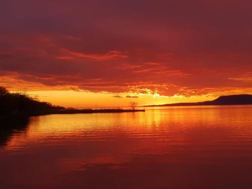 a sunset over a body of water with the sun setting at Magyartenger Apartman Balatonlelle in Balatonlelle