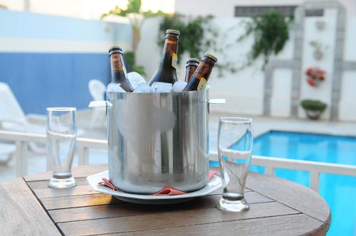 a bucket of beer bottles on a table with two glasses at Hotel Riviera in Araçatuba