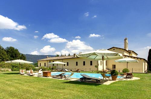 a house with a pool and chairs and umbrellas at San Pietro Sopra Le Acque Resort & Spa in Massa Martana