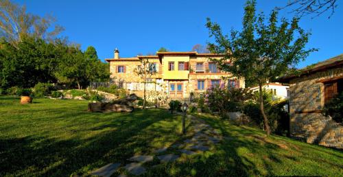 a large house with a grass yard in front of it at Hotel Maistra in Tsagarada