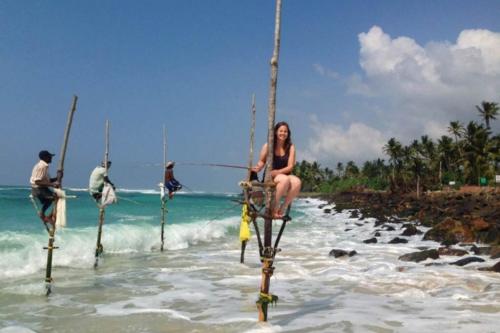 a woman sitting on a pole in the water at NEW SITHI VILLAS in Hikkaduwa