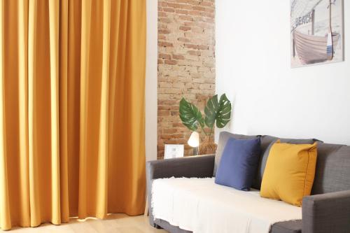 a living room with a couch with yellow curtains at Mediterranean Way - Tarragona Central Apartments in Tarragona