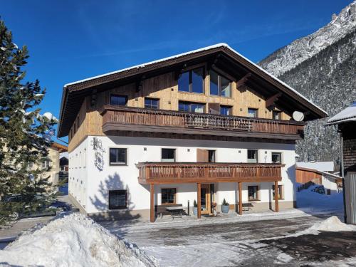 a large building with a balcony in the snow at Gästehaus Sonne in Bichlbach