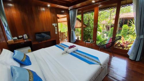 a bedroom with two beds with blue pillows and a window at บ้านสวนในฝัน-ตลาดน้ำท่าคา in Samut Songkhram