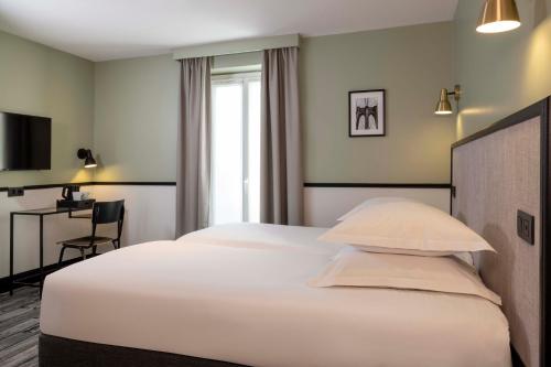 a bedroom with a large white bed and a desk at Hotel de l'Aqueduc in Paris