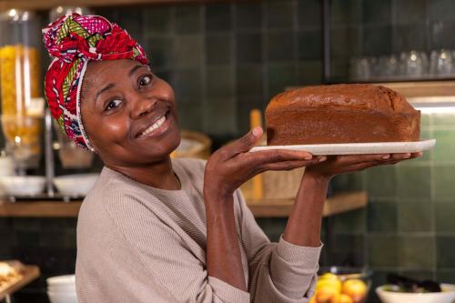 a woman is holding a cake on a plate at Hotel de l'Aqueduc in Paris