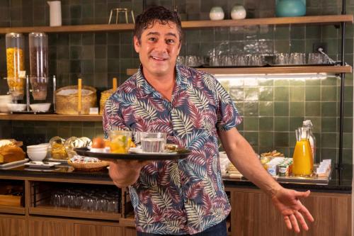 a man holding a plate of food in a kitchen at Hotel de l'Aqueduc in Paris
