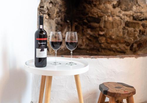 a bottle of wine and two wine glasses on a table at Lotza Traditional House Salakos in Sálakos