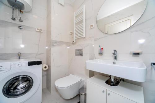 a white bathroom with a washing machine and a sink at Eastside Apartment Bar in Bar