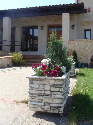 a stone planter with flowers in front of a building at Alojamiento Rural La Henera in San Juan de Ortega