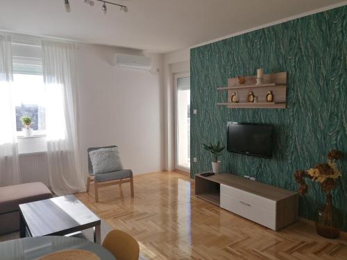 a living room with a flat screen tv on a green wall at Krstić_lux apartman in Subotica