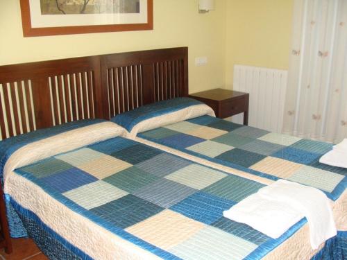 a bed with a checkered blanket on top of it at Alojamiento Rural La Henera in San Juan de Ortega
