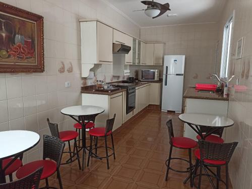 eine Küche mit Tischen und Stühlen sowie einem Kühlschrank in der Unterkunft Pousada Della Nonna in Presidente Prudente