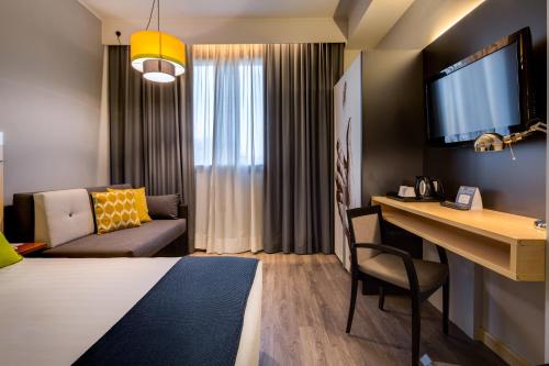 a room with a bed and a desk and a couch at Holiday Inn Bologna - Fiera by IHG in Bologna
