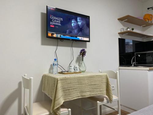 a television hanging on a wall with a table and chairs at Central Studio Apartments in Tirana