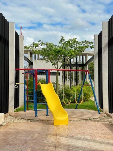 a playground with a yellow slide in a park at Casa Otavia, con alberca para 6 huéspedes y mascotas in Conkal
