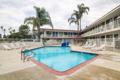 a pool at a hotel with chairs and palm trees at Motel 6-Camarillo, CA in Camarillo