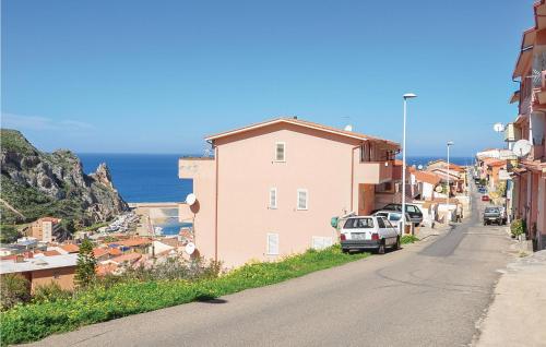 a city street with a pink house and the ocean at Casa Sole Rosso in Buggerru