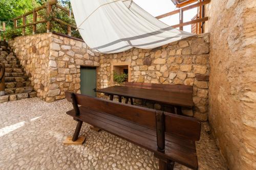 a wooden bench sitting next to a stone wall with an umbrella at B&B Arlanch 8 in Vallarsa